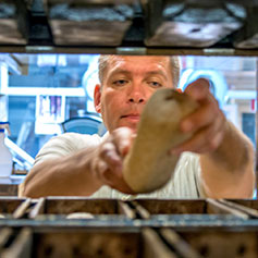 Baker getting bread from the oven