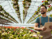 Man stands in greenhouse and holds clipboard