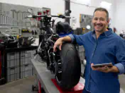 Mechanic rests his arm on a motorcycle in a shop
