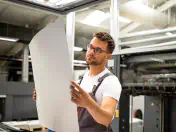 Printing press employer looking at full sheet of paper