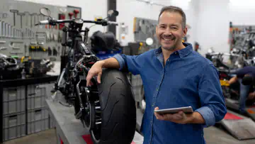 Mechanic rests his arm on a motorcycle in a shop