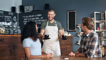 Barista serves cappuccinos to two guests